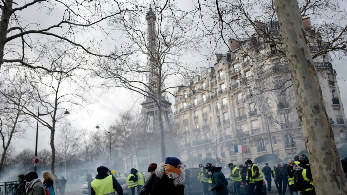 Yellow vest protesters run away from tear gas fired by riot police as they keep pressure on French President Emmanuel Macron's government, for the 13th straight weekend of demonstrations, during a demonstration in Paris, France, Saturday, Feb. 9, 2019.