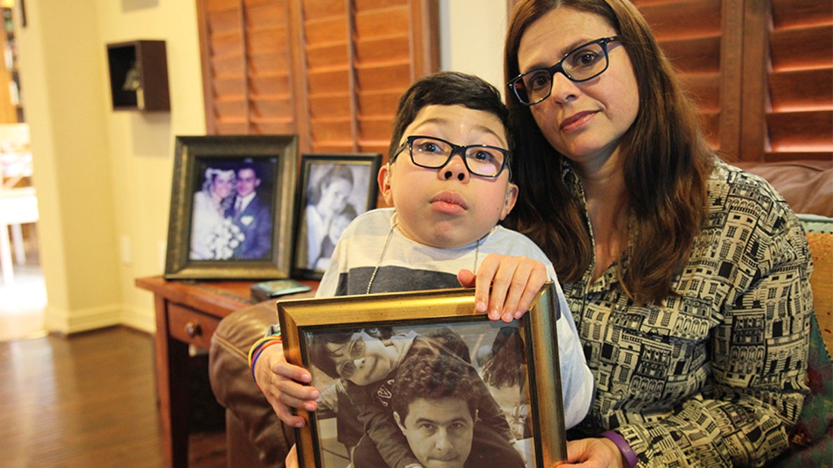 Sergio Cardenas holds a picture of himself with his father Gustavo as he sits on the lap of his mother Maria Elena Cardena, Gustavo's wife, at their home in Katy, Texas, Friday, Feb. 15, 2019. Gustavo, a Citgo executive, has been held in detention by the Venezuelan government along with five other Citgo employees since November of 2017, but their preliminary hearing has been postponed 12 times, leaving the families to question whether their loved ones are being held as pawns in a high-stakes political negotiation.
