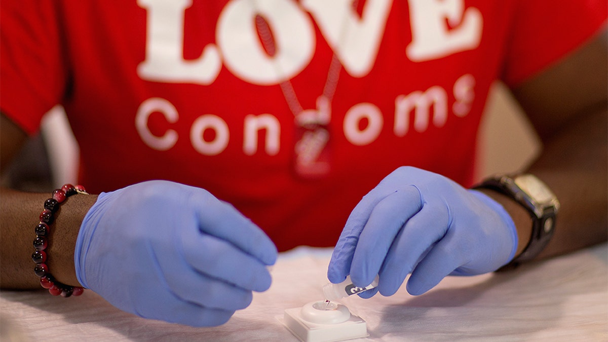 FILE - In this June 27, 2013 file photo, Reggie Batiste, program manager with AIDS Healthcare Foundation, administers a free HIV test as part of National HIV Testing Day in Atlanta. Just three weeks after President Donald Trump launched a campaign to end the U.S. HIV epidemic by 2030, new data suggests shows has already stalled. (AP Photo/David Goldman, File)
