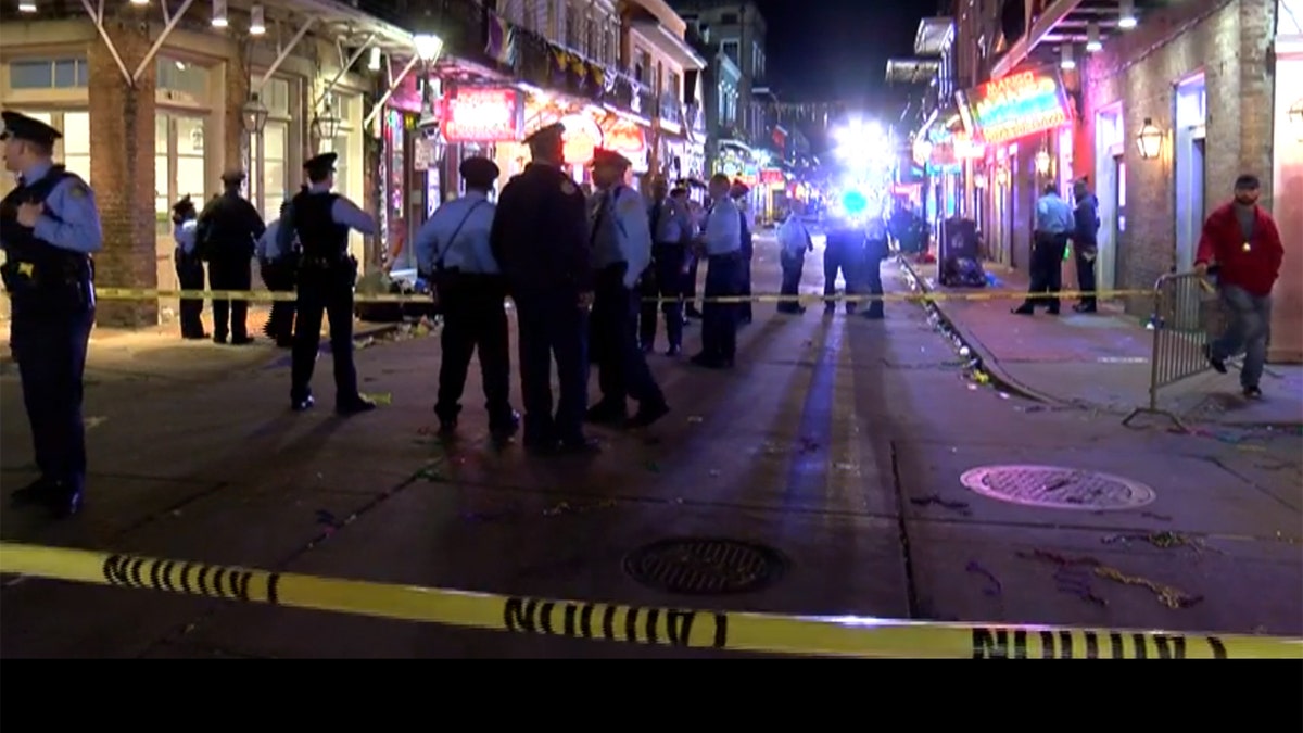Police in middle of street behind crime scene tape
