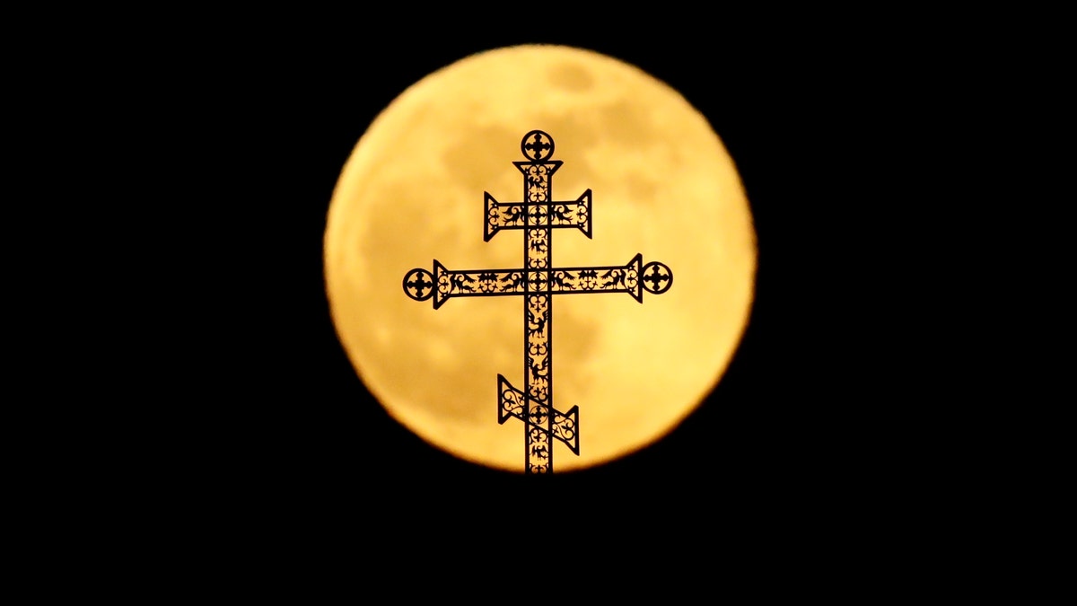 The full moon rises behind a steeple with crosses of an Orthodox church in Minsk, Belarus, Tuesday, Feb. 19, 2019.