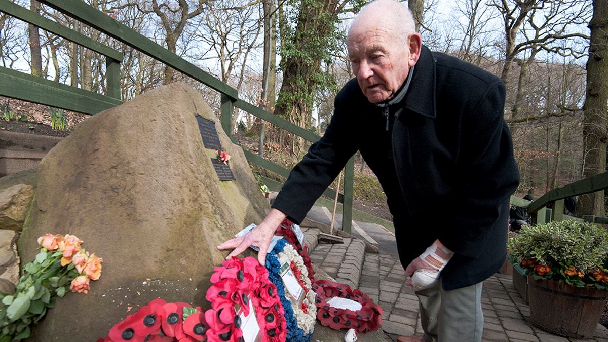 Tony Foulds tends to a memorial honouring 10 U.S. airmen who died in a plane crash in Endcliffe Park, Sheffield, England, Wednesday, Feb. 13, 2019. Foulds was just a kid running around in the park on Feb. 22, 1944 when a U.S. Air Force crew decided to crash and die rather than take the chance of hitting them. He's dreamed of honoring them for decades.