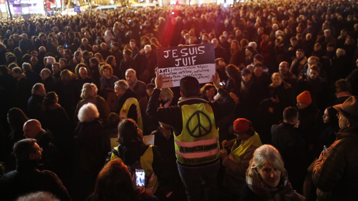 A man wearing a yellow vest holds a placard reading "I am jew", during a gathering at the Republique square to protest against anti-Semitism, in Paris, France, Tuesday, Feb. 19, 2019. In Paris and dozens of other French cities, ordinary citizens and officials across the political spectrum geared up Tuesday to march and rally against anti-Semitism, following a series of anti-Semitic acts that shocked the nation.
