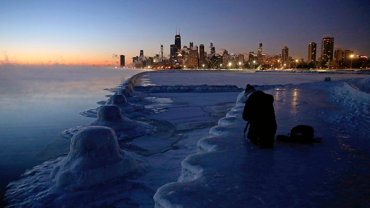 A photographer sets up his tripod on the shore of Lake Michigan before sunrise, Thursday, Jan. 31, 2019, in Chicago. (Associated Press)