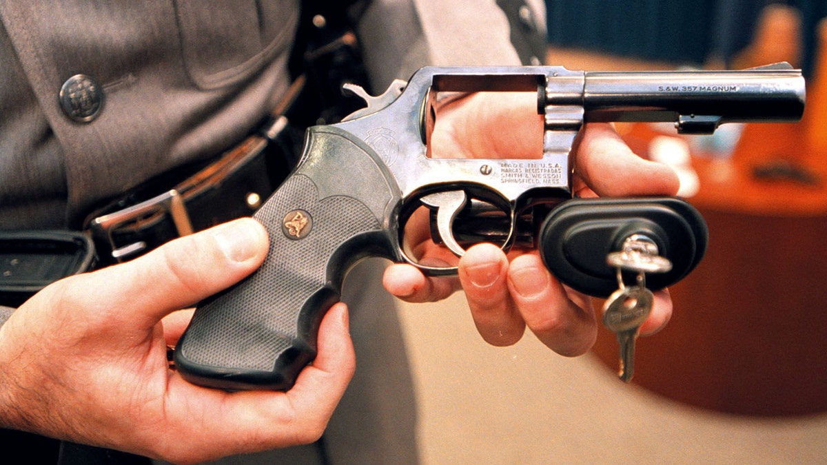 A New York State police officer displays a handgun with a child safety lock on March 15, 2000.