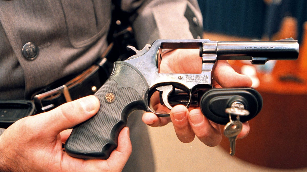 A New York State police officer displays a handgun with a child safety lock on March 15, 2000.