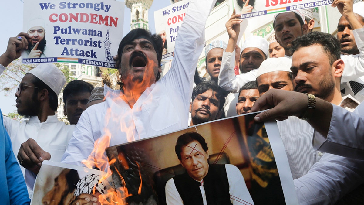 Indian Muslims burn posters of Pakistani prime minister Imran Khan, center, and Jaish-e-Mohammed leader Masood Azhar, during a protest against Thursday's attack on a paramilitary convoy in Kashmir that killed at least 40, in Mumbai, India, Friday. 