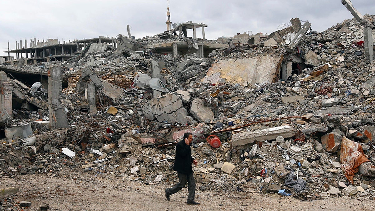 A man walks past damaged buildings in the northern Syrian town of Kobani January 30, 2015. 