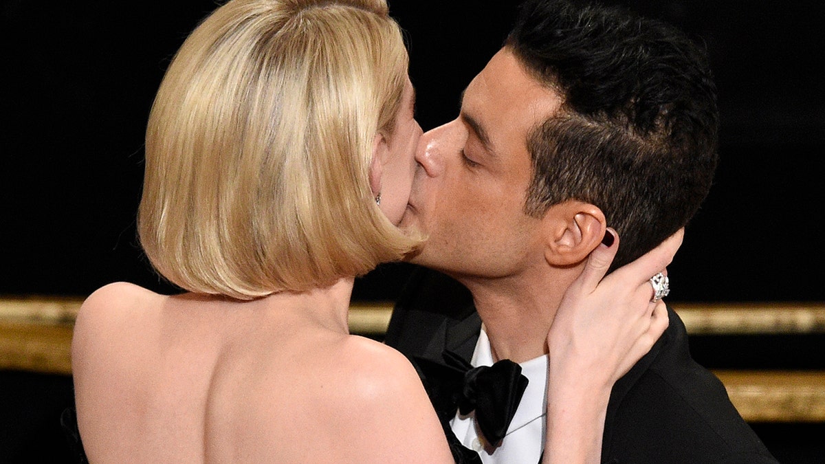 Lucy Boynton, left, kisses Rami Malek in the audience after he is announced winner of the award for best performance by an actor in a leading role for 