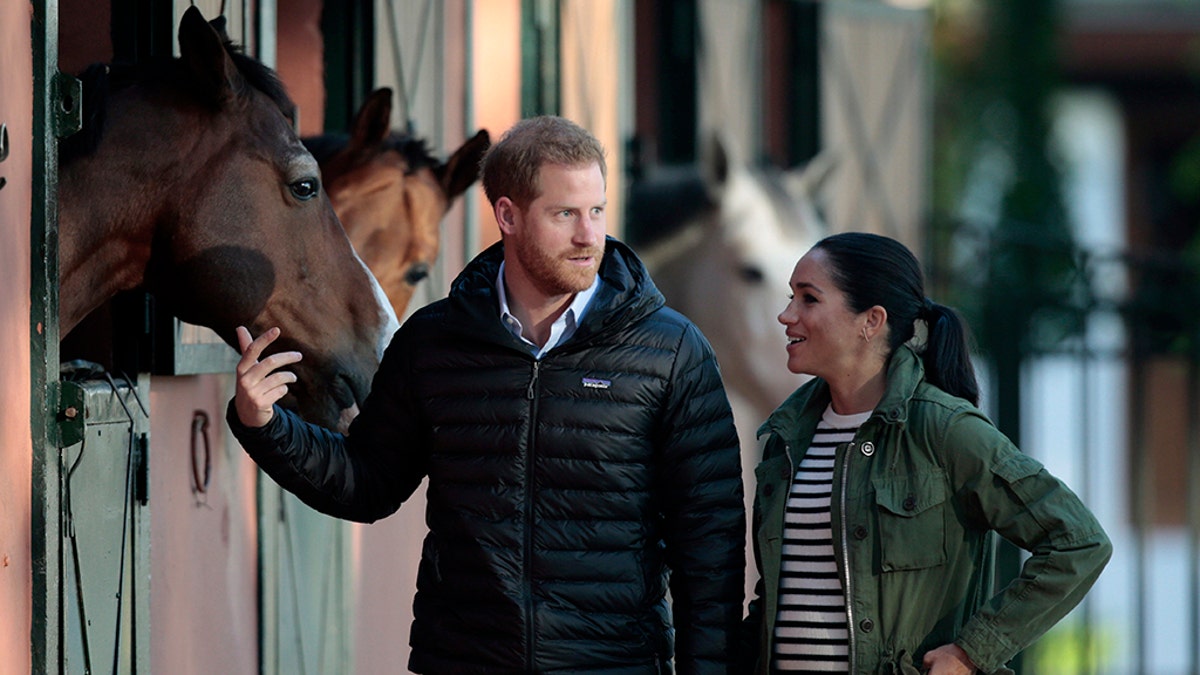 Britain's Prince Harry and Meghan, Duchess of Sussex, walk together during a visit to the Moroccan Royal Equestrian Sports Complex in Rabat, Morocco, Monday Feb. 25, 2019. The royal couple, who are expecting their first child in Spring 2019, are visiting the prestigious equestrian club to see the use of horses in therapy for children with disabilities. (AP Photo/Mosa'ab Elshamy)