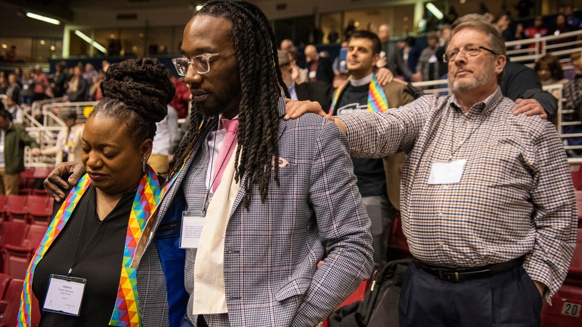 Adama Brown-Hathasway, left, The Rev. Dr. Jay Williams, both from Boston, and Ric Holladay of Kentucky join in prayer during the 2019 Special Session of the General Conference of The United Methodist Church in St. Louis