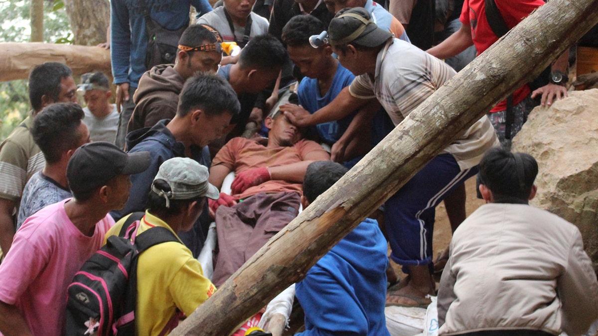 Rescuers carry a survivor from inside a collapsed mine in Bolaang Mongondow, North Sulawesi, Indonesia, Wednesday, Feb. 27, 2019.