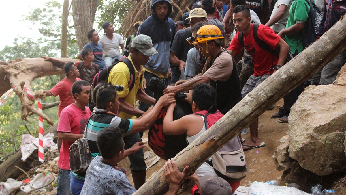 Rescuers carry the body of a victim of a collapsed mine in Bolaang Mongondow, North Sulawesi, Indonesia, Wednesday, Feb. 27, 2019.