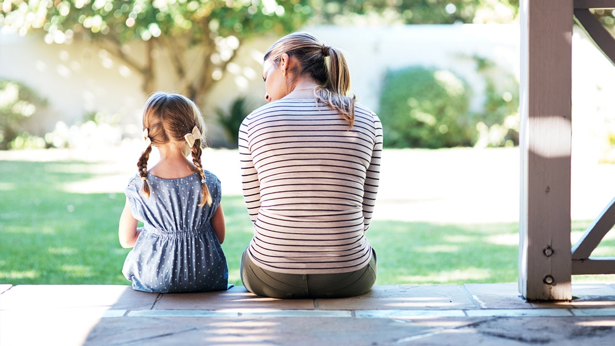 Mother and daughter sitting on steps. iStock