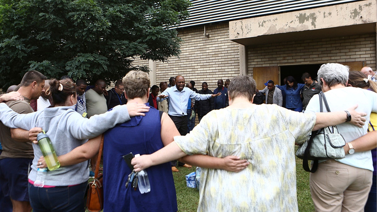 A pastor leads people in prayer at the site of a walkway collapse at the Driehoek High School in Vanderbijlpark, South Africa, Friday, Feb. 1, 2019. At least 3 students were killed and scores injured at the school near Johannesburg, a South African official said.