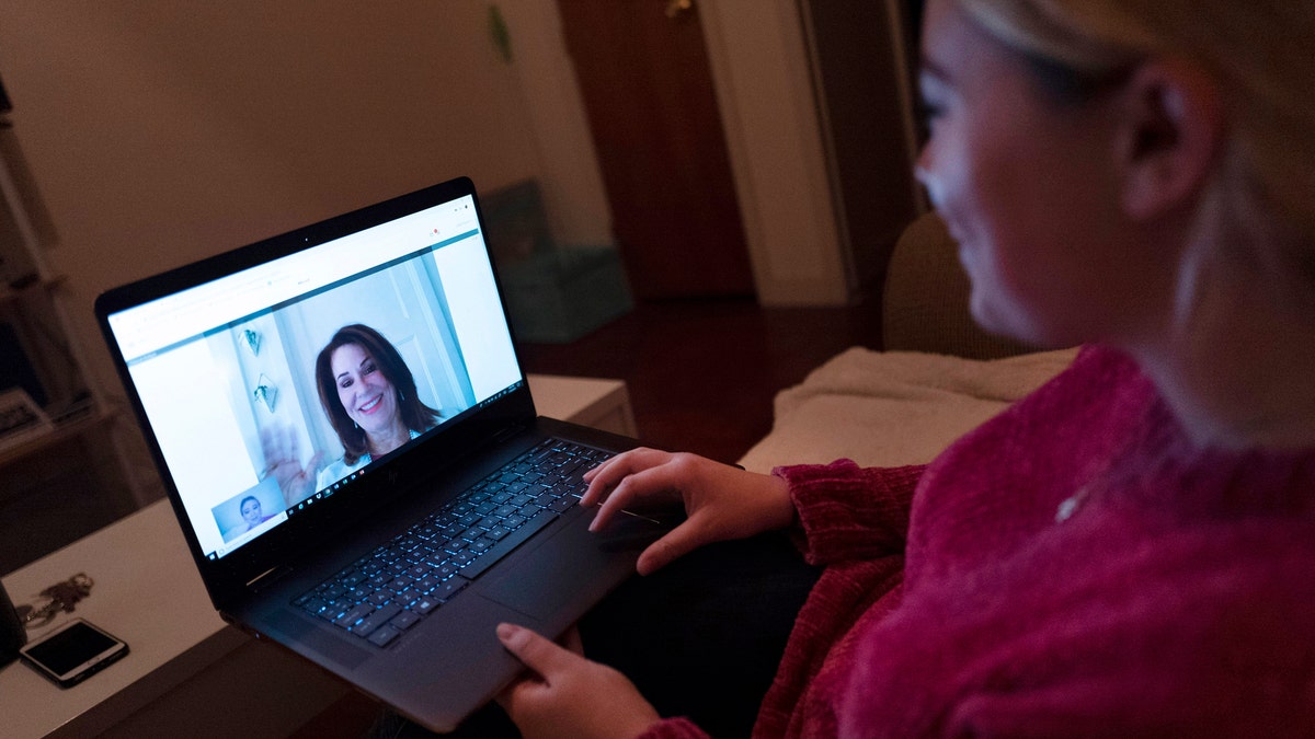 In this Jan. 14, 2019 photo, Caitlin Powers sits in the living room of her Brooklyn apartment in New York, and has a telemedicine video conference with physician, Dr. Deborah Mulligan. Widespread smartphone use, looser regulations and employer enthusiasm are helping to expand access to telemedicine, where patients interact with doctors and nurses from afar, often through a secure video connection. (AP Photo/Mark Lennihan)