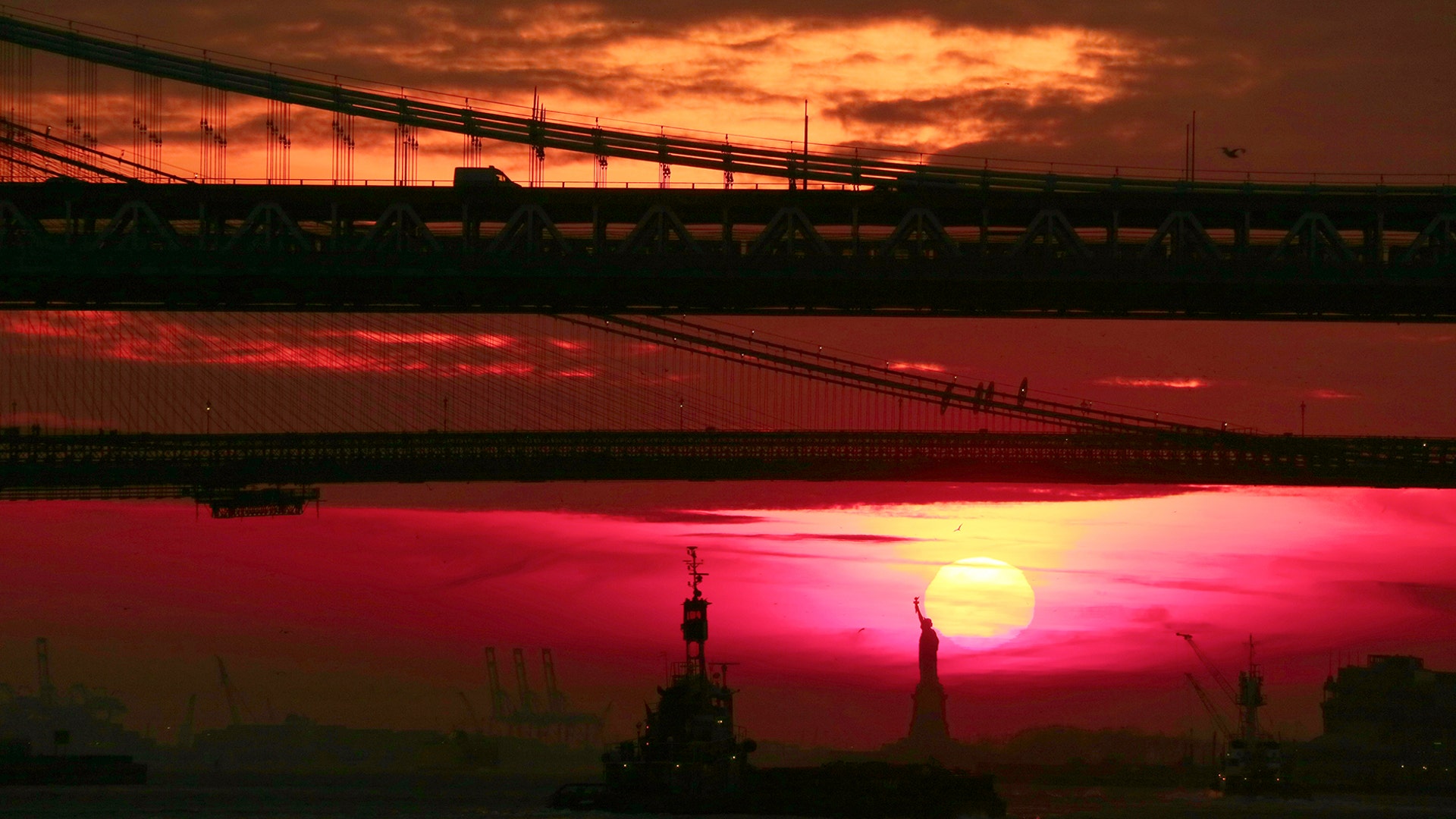 The sun sets behind the Statue of Liberty, Brooklyn Bridge and Manhattan Bridge in New York City, Feb. 2, 2019.