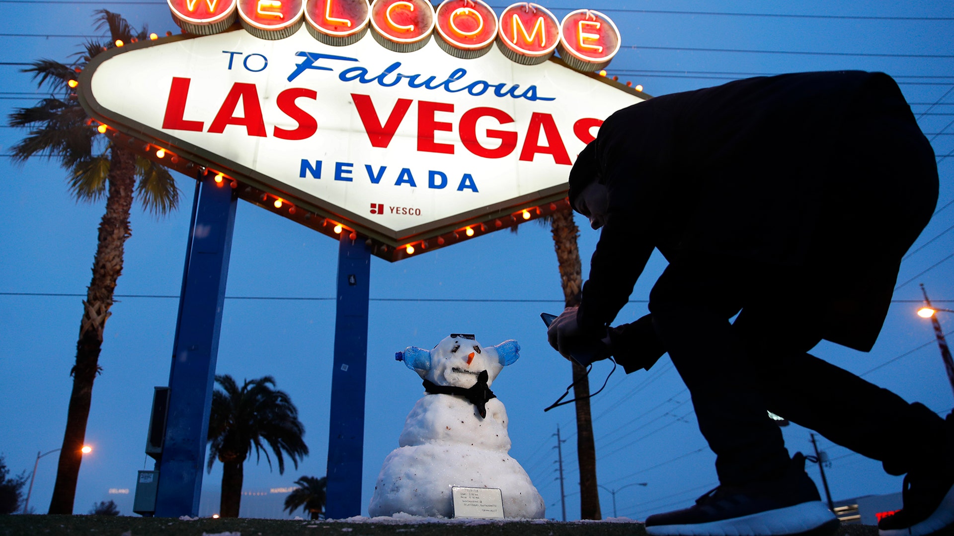 A man takes a picture of a small snowman at the "Welcome to Fabulous Las Vegas" sign along the Las Vegas Strip, Feb. 21, 2019. 