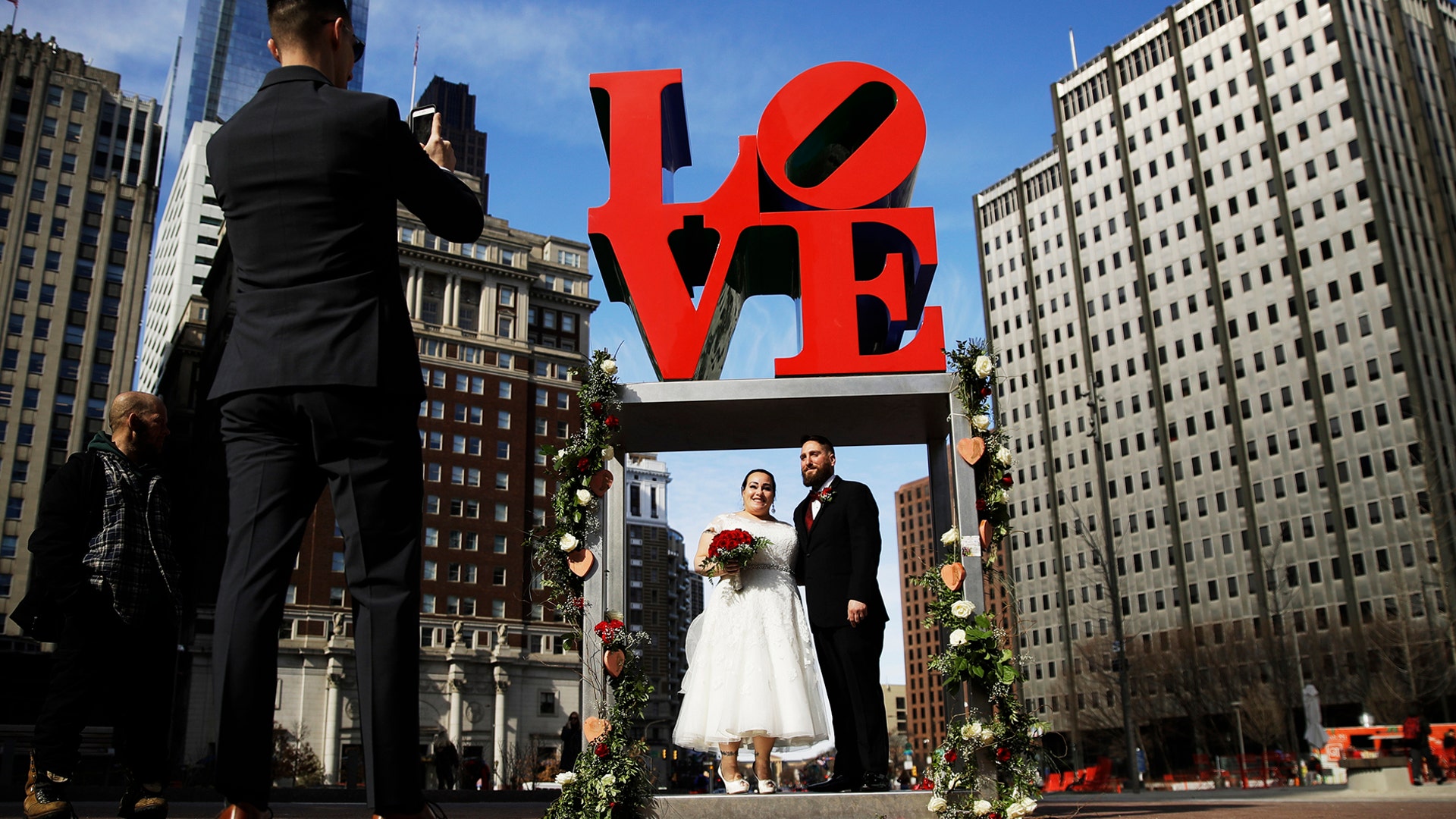 Newlyweds Jennifer and Paul Raffa pose for a photograph with the Robert Indiana sculpture "LOVE" at John F. Kennedy Plaza on Valentine's Day in Philadelphia, Feb. 14, 2019.