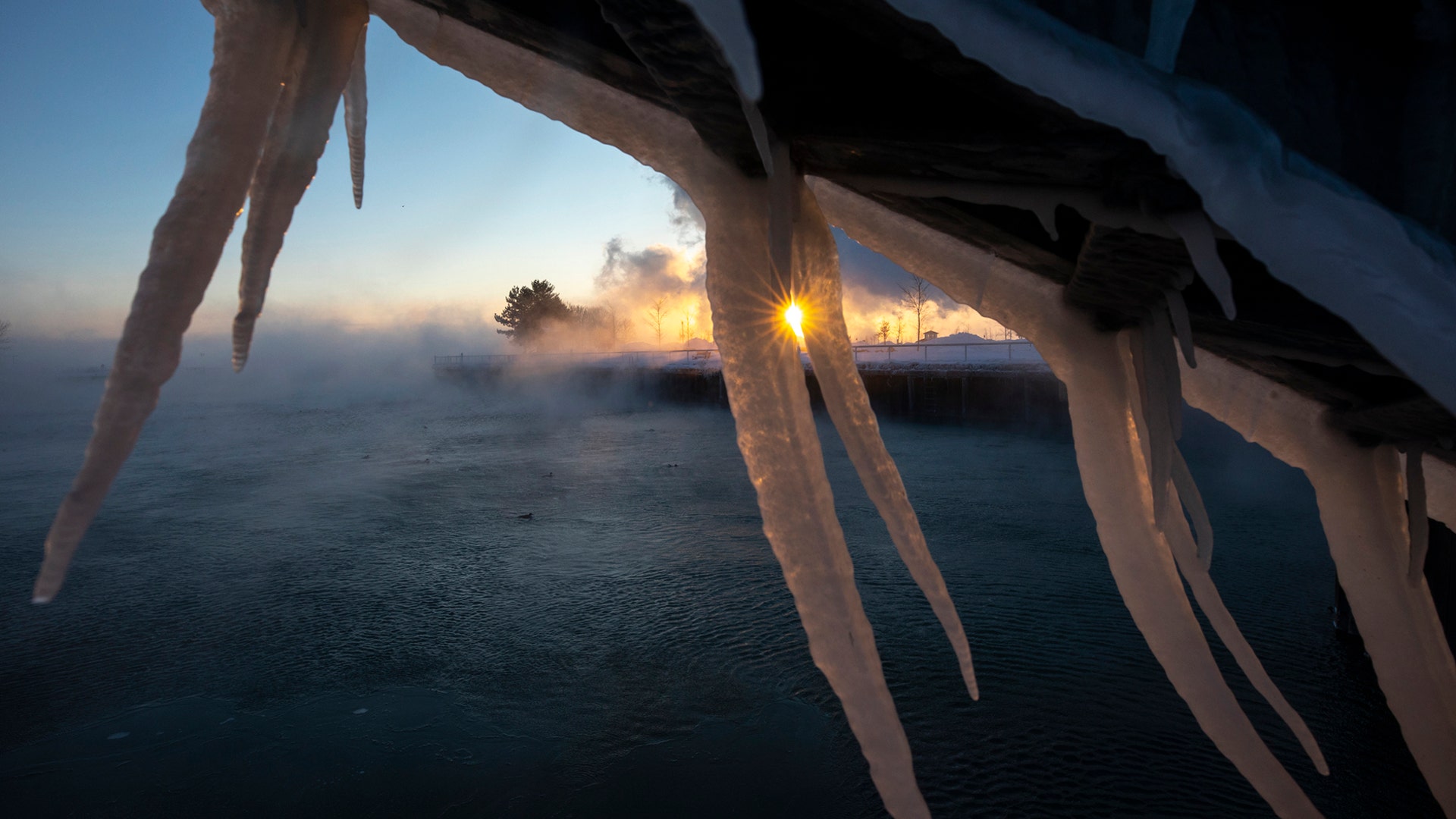 The sun rises behind icicles formed on the harbor in Port Washington, Wisconsin, January 30, 2019.