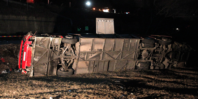 A bus lays overturned at the crash site at village of Laskarci, west of Skopje, North Macedonia, Wednesday, Feb. 13, 2019. Macedonia's health minister says some have died and many are injured in the bus crash, carrying workers on a highway west of the capital, Skopje. (AP Photo/Boris Grdanoski)
