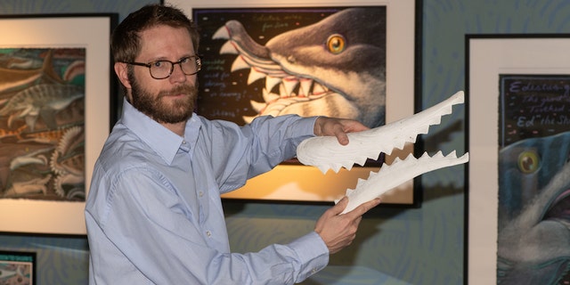 Idaho Museum of Natural History Director Leif Tapanila holds a replica of the Edestus' sharp-toothed jaw.