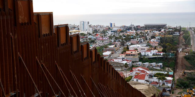 In this Jan 15, 2019 image, a section of newly-replaced border wall separates Tijuana, Mexico, above left, from San Diego, right, in San Diego. Border Patrol officials say some Mexican homes and structures encroach on U.S. soil posing a dilemma for authorities when replacing the wall. [AP Photo/Gregory Bull)