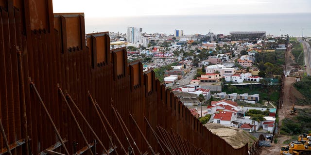 In this Jan 15, 2019 image, a section of newly-replaced border wall separates Tijuana, Mexico, above left, from San Diego, right, in San Diego. Border Patrol officials say some Mexican homes and structures encroach on U.S. soil posing a dilemma for authorities when replacing the wall. [AP Photo/Gregory Bull)