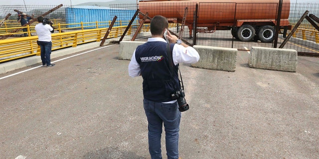 An immigration official observes a fuel tanker, cargo trailers and makeshift fencing, used as barricades by Venezuelan authorities attempting to block humanitarian aid entering from Colombia on the Tienditas International Bridge.
