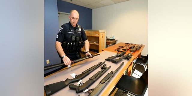 In this May 23, 2018, photo, Seattle Police Crisis Response Team Sgt. Eric Pisconski displays guns seized from people deemed to be a danger to themselves or others. Since last year's mass shooting at a Florida high school, states have seen a surge of interest in laws intended to make it easier to disarm people who show signs of being violent or suicidal. Washington voters approved such a law overwhelmingly in 2016. (Greg Gilbert/The Seattle Times via AP)