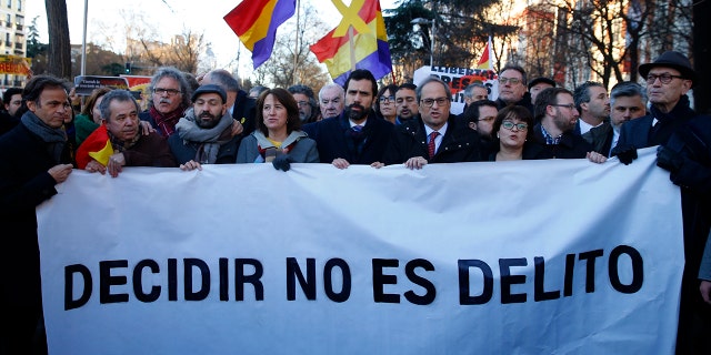 The president of Catalonian Parliament, Roger Torrent, center, and the Catalan regional President Quim Torra, center right, hold a placard that reads in Spanish: " To Choose is not a Crime", outside the Spanish Supreme Court in Madrid.