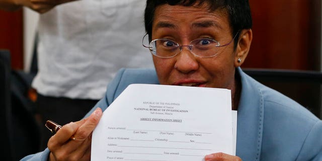 Maria Ressa, the award-winning head of a Philippine online news site Rappler that has aggressively covered President Rodrigo Duterte's policies, shows an arrest form after being arrested by National Bureau of Investigation agents in a libel case Wednesday, Feb. 13, 2019, in Manila, Philippines.
