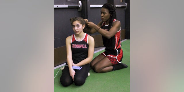 In this Thursday, Feb. 7, 2019 photo, Cromwell High School transgender athlete Andraya Yearwood , right, braids the hair of teammate Taylor Santos, left, during a break at a track meet at Hillhouse High School in New Haven, Conn. Yearwood, a 17-year-old junior at Cromwell High School, is one of two transgender high school sprinters in Connecticut, transitioning to female. (AP Photo/Pat Eaton-Robb)