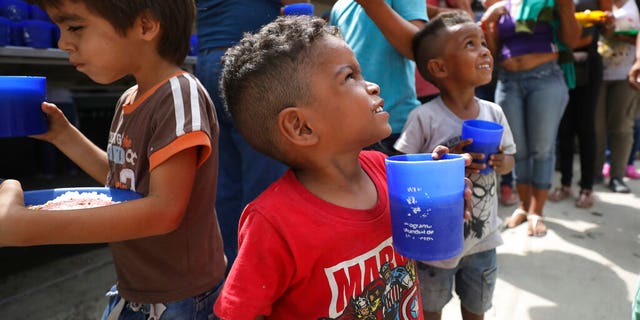 Venezuelan boys holding cups of a grape-flavored drink, part of the free lunch that is given out daily at the "Divina Providencia" migrant shelter in La Parada, near Cucuta, Colombia, on the border with Venezuela, on Monday. (AP Photo/Fernando Vergara)