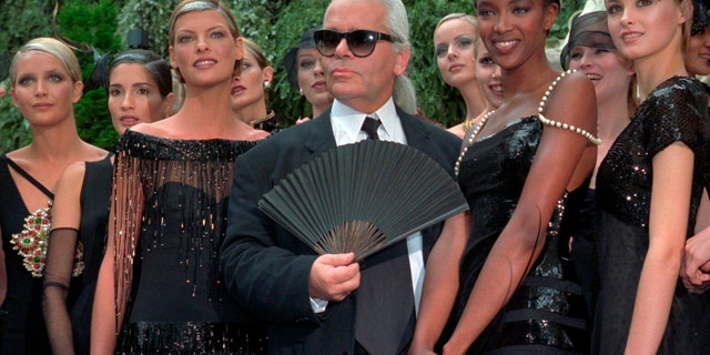 Karl Lagerfeld surrounded by Canadian model Linda Evangelista, left, and British model Naomi Campbell, right, and other models after the presentation of his 1996-97 fall-winter haute couture fashion collection for Chanel in Paris, on July 9, 1996. (AP Photo/Lionel Cironneau, File)