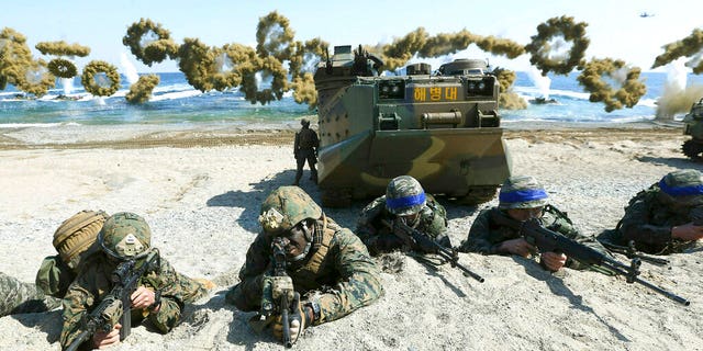 Marines of the U.S., left, and South Korea, wearing blue headbands on their helmets, taking positions after landing on a beach during a joint military exercise in 2016. (Kim Jun-bum/Yonhap via AP, File)