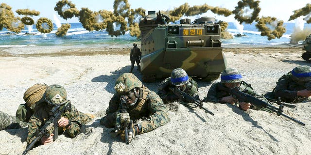 Marines of the U.S., left, and South Korea, wearing blue headbands on their helmets, taking positions after landing on a beach during a joint military exercise in 2016. (Kim Jun-bum/Yonhap via AP, File)