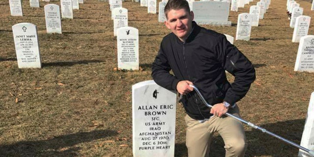 In this Jan. 30, 2018, photo provided by Vicki Hencely, her son Army Spc. Winston Hencely poses for a photo with his service dog at Arlington National Cemetery in Arlington, Va. Hencely, a U.S. soldier grievously wounded in a suicide bombing two years ago in Afghanistan, filed suit Wednesday, Feb. 20, 2019, against an American defense contractor that employed the bomber, saying it failed to supervise the man as he built an explosive vest on the job using the company's tools and parts. (Vicki Hencely via AP)