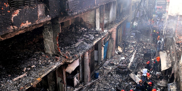 Locals and firefighters gather around buildings that caught fire in Dhaka, Bangladesh, Feb. 21, 2019. A devastating fire raced through at least five buildings in an old part of Bangladesh's capital and killed scores of people. 
