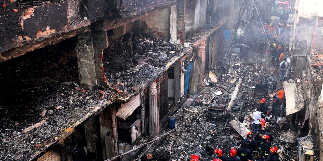 Locals and firefighters gather around buildings that caught fire in Dhaka, Bangladesh, Feb. 21, 2019. A devastating fire raced through at least five buildings in an old part of Bangladesh's capital and killed scores of people. 