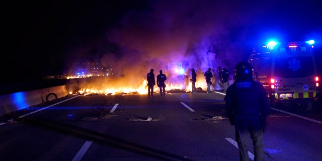 Police officers try to remove burning tires, set by demonstrators to block a highway in protest of the imprisonment of pro-independence political leaders during a general strike in Catalonia, Spain, Thursday, Feb. 21.