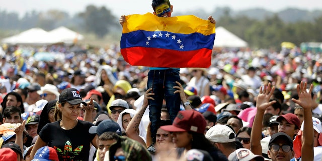A child holds a Venezuelan flag during the Venezuela Aid Live concert on the Colombian side of Tienditas International Bridge on the outskirts of Cucuta, Colombia, on the border with Venezuela, Friday, Feb. 22, 2019. (AP Photo/Fernando Vergara)