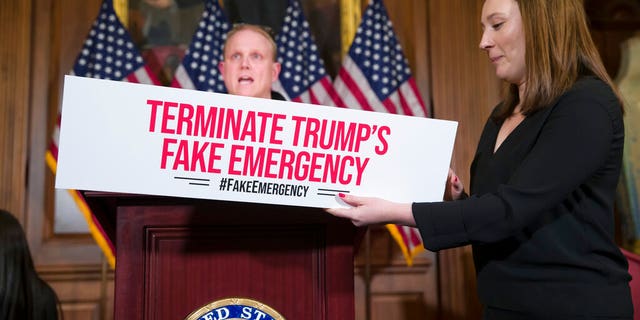 An aide places a placard on the podium, as a journalist does a sound check, before a media availability about a resolution to block President Donald Trump's emergency border security declaration on Capitol Hill, Monday, Feb. 25, 2019 in Washington. (AP Photo/Alex Brandon)