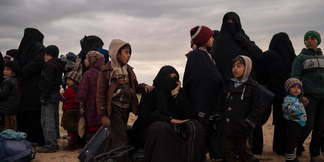 Women and children evacuated out of the last territory held by Islamic State militants wait to be screened by U.S.-backed Syrian Democratic Forces (SDF) in the desert outside Baghouz, Syria, Wednesday, Feb. 27, 2019.