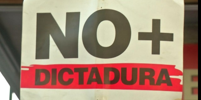 Protesters hold up signs, demanding an end to dictatorship in their country