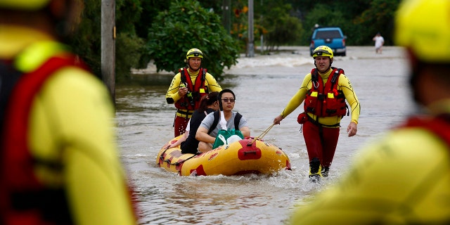 In this Sunday, Feb. 3, 2019, photo, Queensland Fire and Emergency Services crew members use an inflatable boat to pull residents through floodwaters at Hermit Park in Townsville, Australia.