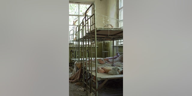 Ukraine: senge i et tidligere daginstitution ruster langsomt væk. HAUNTING fotografier viser, hvordan naturen genvinder en by forladt efter en atomkatastrofe 33 år siden. Den hollandske fotograf, 47, rejste til 18-mile udelukkelsesområdet omkring Tjernobyl i det nordlige Ukraine i 2016 og 2018 for at fotografere de spøgelsesrige ruiner. (Kredit: Mediadrumimages)