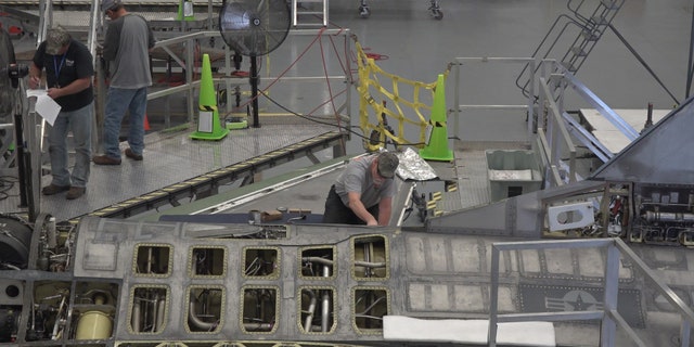 A "boneyard wrangler" working on a fighter jet to refurbish for Boeing's autonomous flying testing.