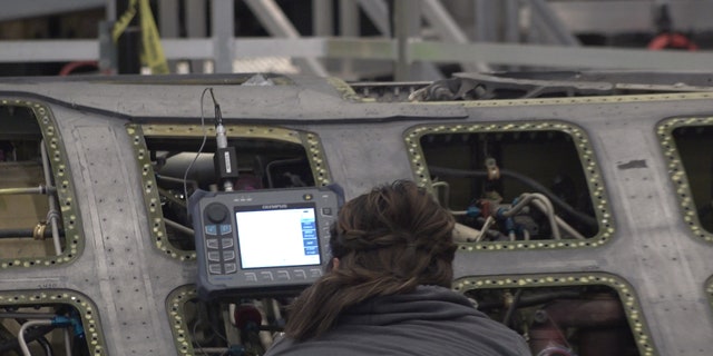 A "boneyard wrangler" working on a fighter jet to refurbish.