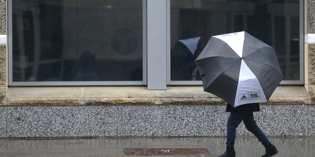 A person huddles under an umbrella as rain falls in Sacramento, Calif., Tuesday, Feb. 26, 2019. (AP Photo/Rich Pedroncelli)